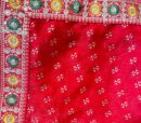 Vibrant silk red saree with intricate floral borders include a dark green blouse piece , perfect for a festive look.