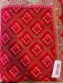 Red silk saree with traditional bandhani-inspired patterns and a rich golden embroidered border with blouse piece